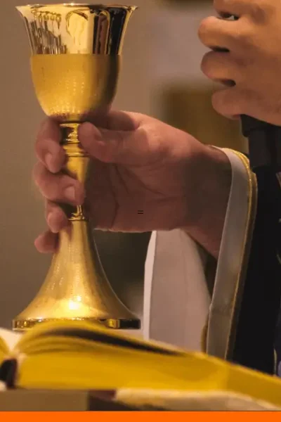 Celebración de eucaristía transmitida en línea, con cáliz, hostia y Biblia sobre un altar iluminado.